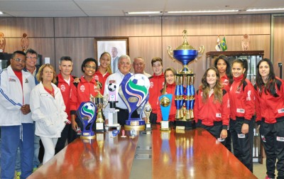 Prefeito Tuíze e secretário Carlinhos Bertagnolli, com a equipe de futsal feminino de Itu e as taças conquistadas.